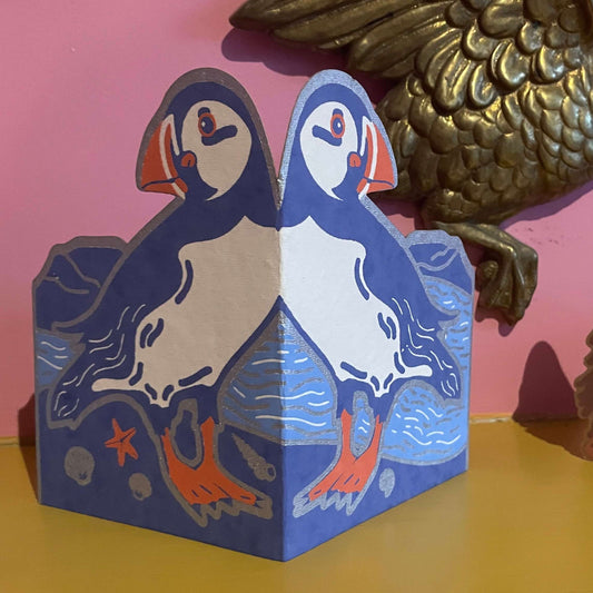 Fold out puffin card on a yellow surface with pink background