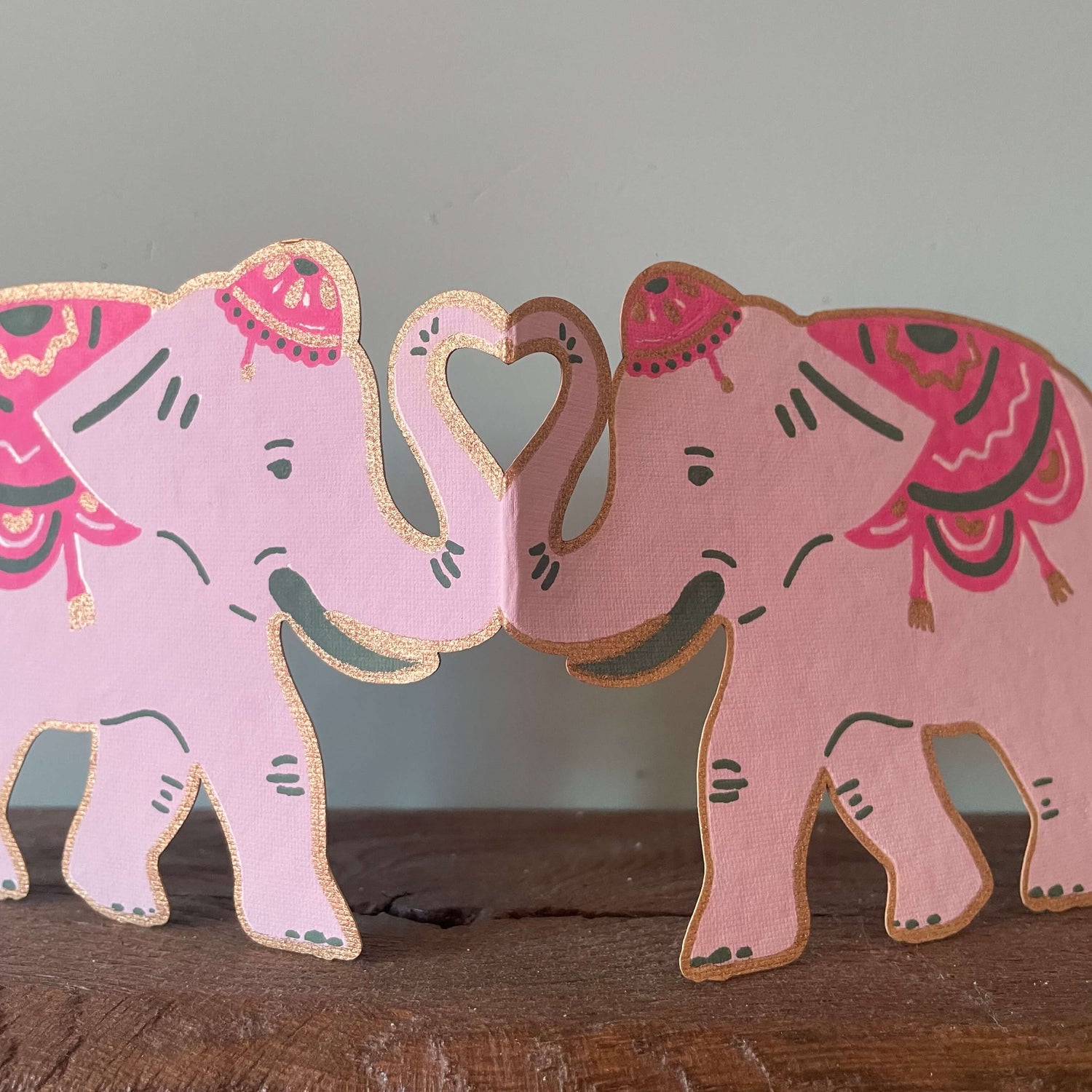 Decorative pink elephants on a wooden surface