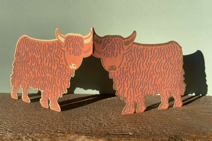 Highland cow card on a wooden surface with a light green background.