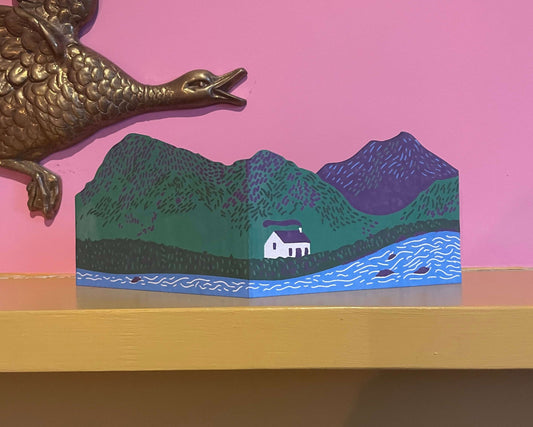 Decorative card with a landscape design on a pink wall with gold duck decorations.